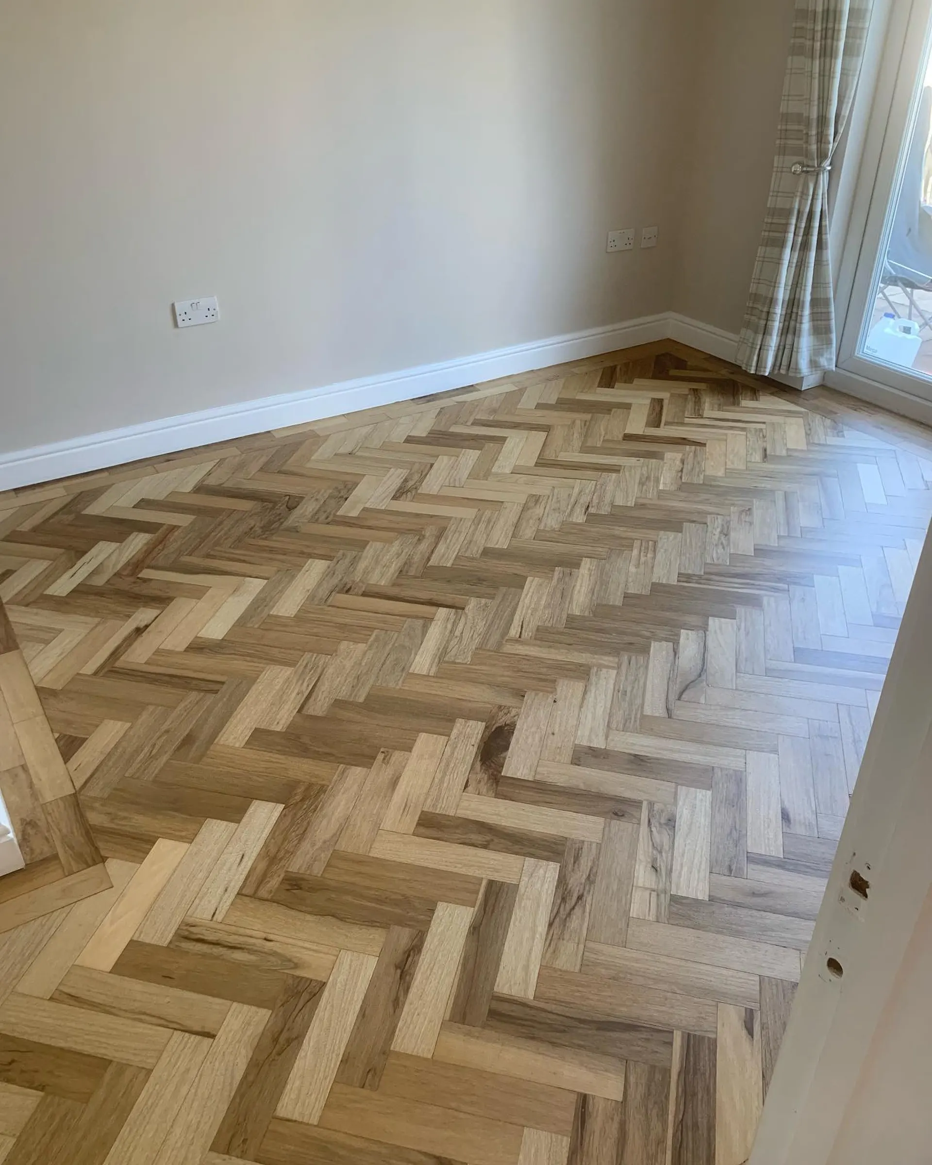 Parquet en chevrons rénové près d'une baie vitrée