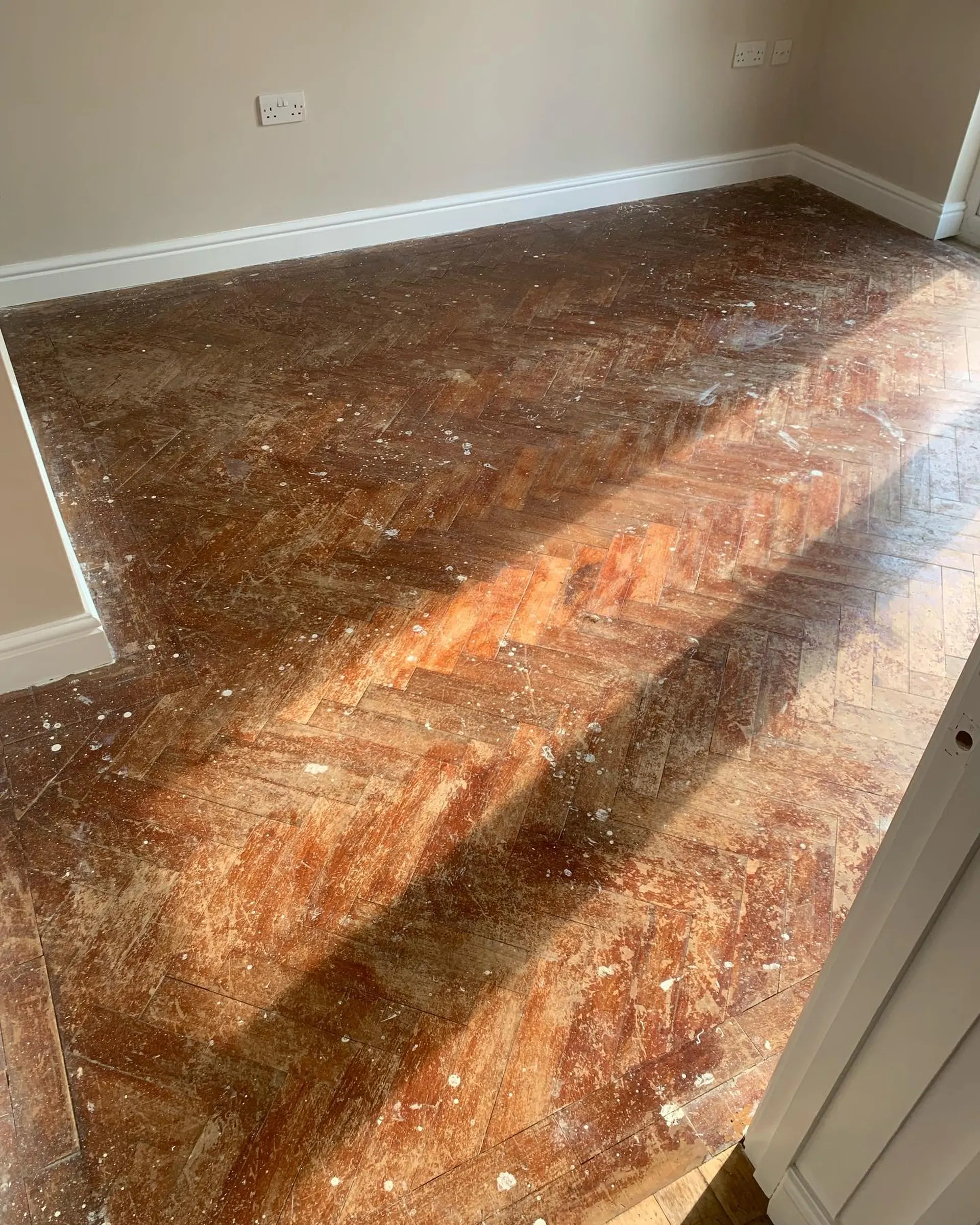 Parquet en chevrons près d'une baie vitrée, avant rénovation